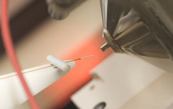 Close-up view of scientific equipment featuring a metal cone and a thin, connected probe.